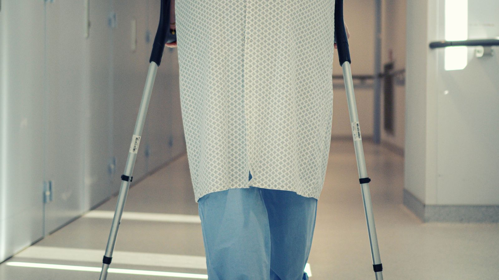 Patient walking with crutches along a hospital corridor during early recovery after joint replacement surgery