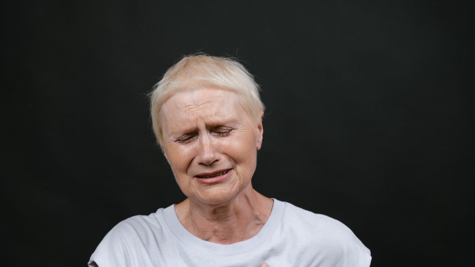 Older woman in visible discomfort, illustrating the atypical and silent heart attack symptoms that are often missed